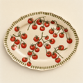 Large oval ivory ceramic serving platter hand-painted with scattered vine tomatoes and a scalloped olive rim